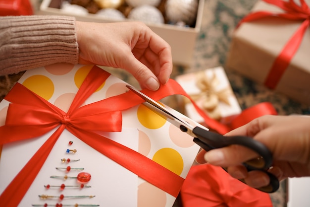 Free photo woman wrapping christmas gift while sitting on the carped in the living room