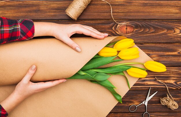 Woman wrapping tulips bouquet in pack paper