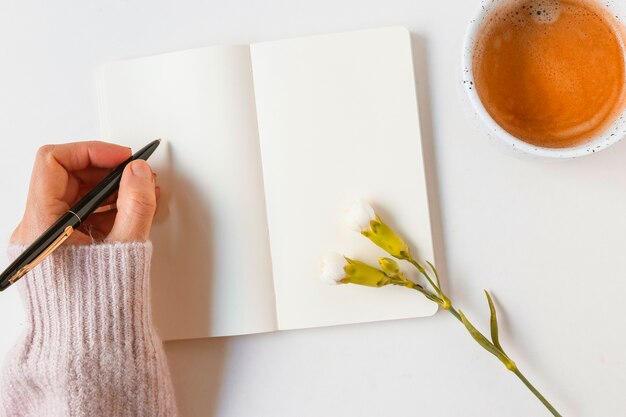 Woman writing on blank notebook with pen over white background