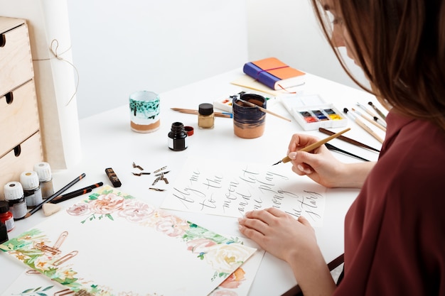 Woman writing calligraphy on postcards