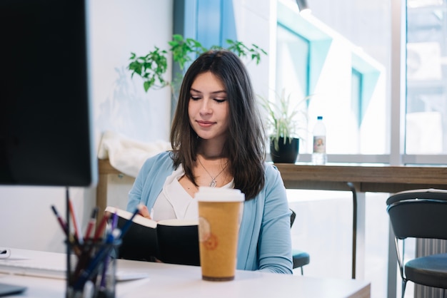 Woman writing in notebook in office