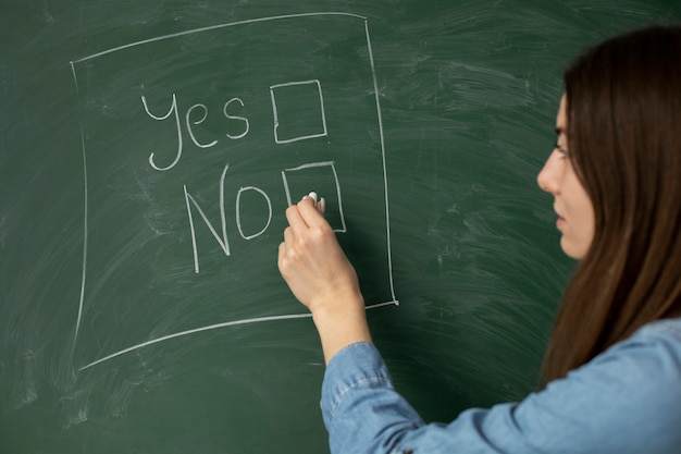 Free photo woman writing with chalk on green board