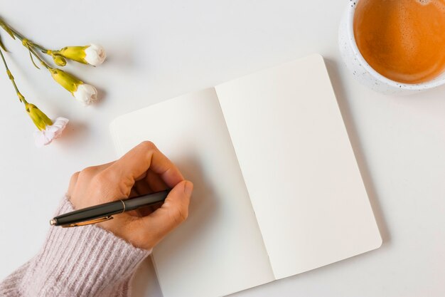 Woman writing with pen on blank page against white background