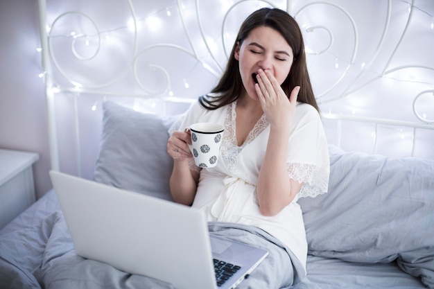 Woman yawning at laptop