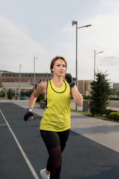 黄色と黒のスポーツ服の女性トレーニング、通りを走っています。