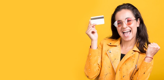 Woman in yellow jacket holding credit card copy space