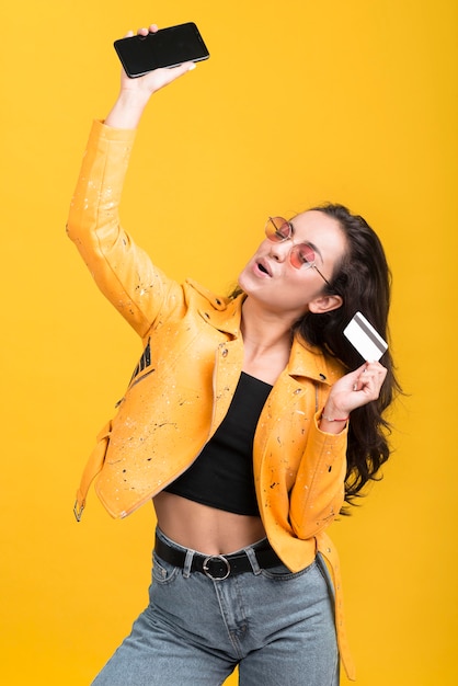 Woman in yellow jacket holding her mobile phone in the air