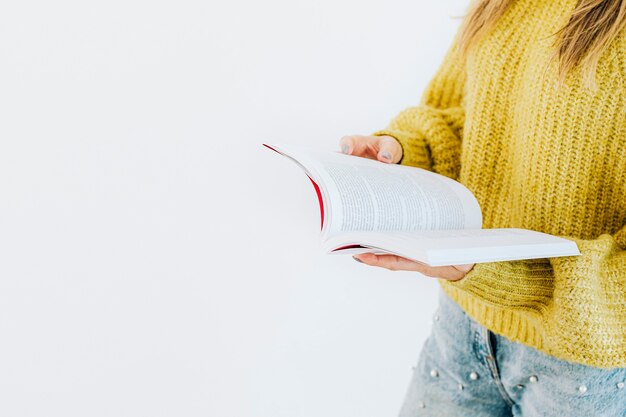 Woman in a yellow knitted sweater reading a book