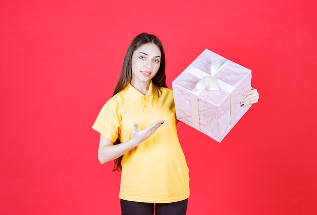 woman in yellow shirt holding a pink gift box. 