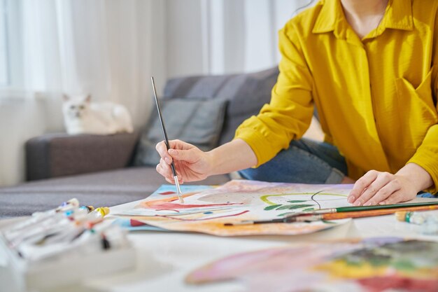 A woman in yellow shirt painting and looking involved