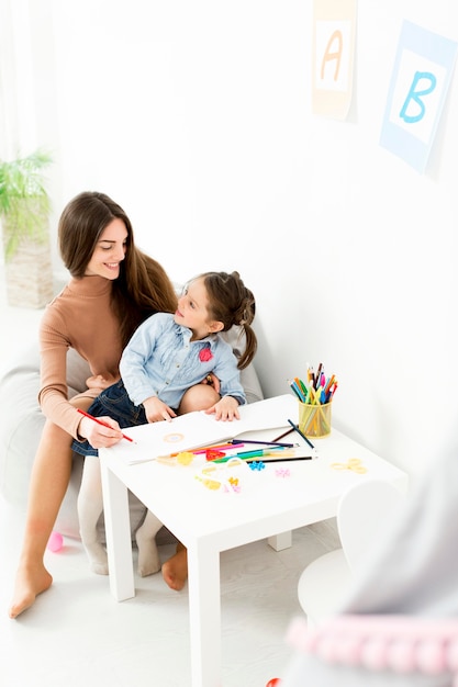 Free photo woman and young girl drawing together at desk