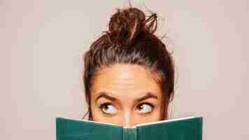 Free photo womans face behind a book