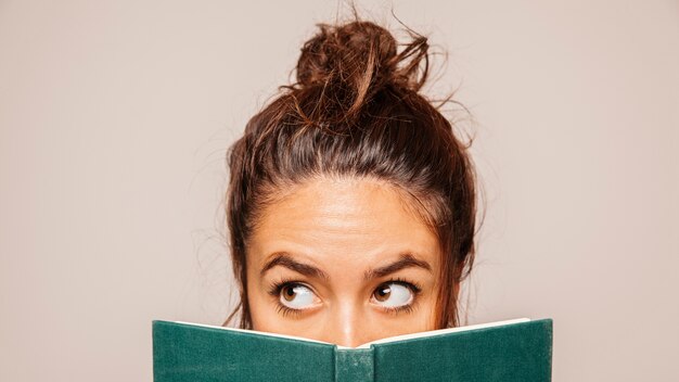 Womans face behind a book