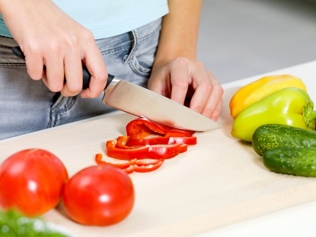 キッチンの机の上で野菜を手で切る女性