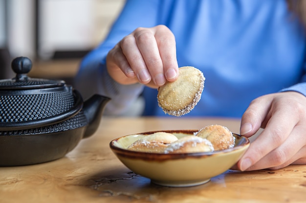 Foto gratuita la mano di una donna prende un biscotto a forma di noce con latte condensato