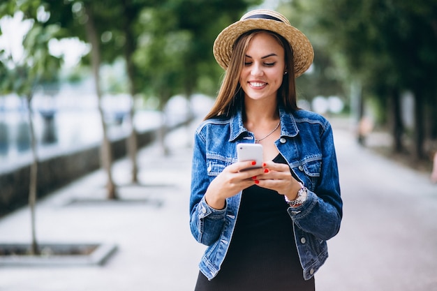 Free photo womanwearing dress and hat outside in park with phone