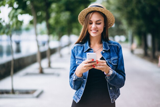 Womanwearing dress and hat outside in park with phone