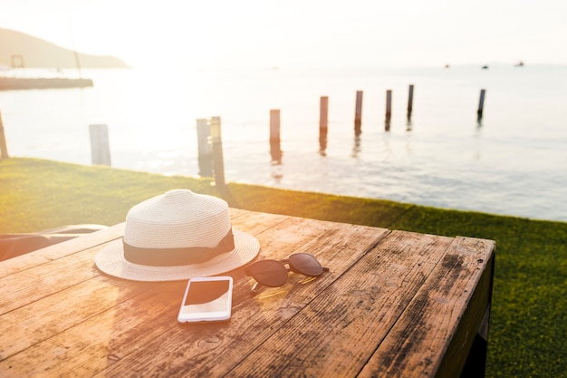 Women accessories on wooden table in front of sea