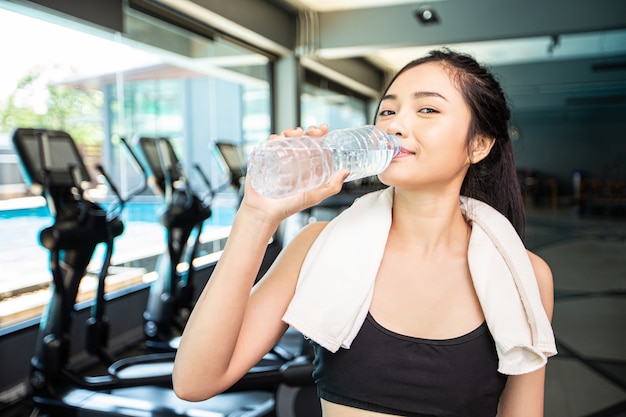 Le donne dopo l'esercizio bevono acqua da bottiglie e fazzoletti in palestra.