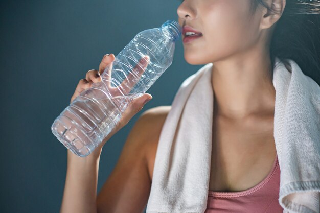 운동 후 여성은 체육관에서 병과 손수건에서 물을 마신다.