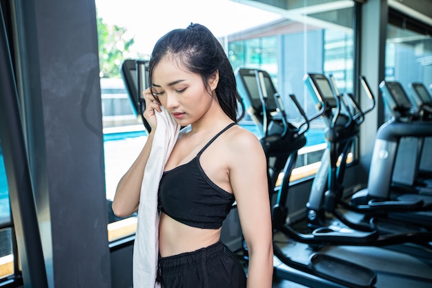 Women after exercising, wipe the face with a white cloth in the gym.