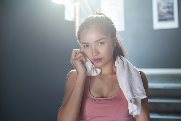 Women after exercising, wipe the face with a white cloth in the gym.