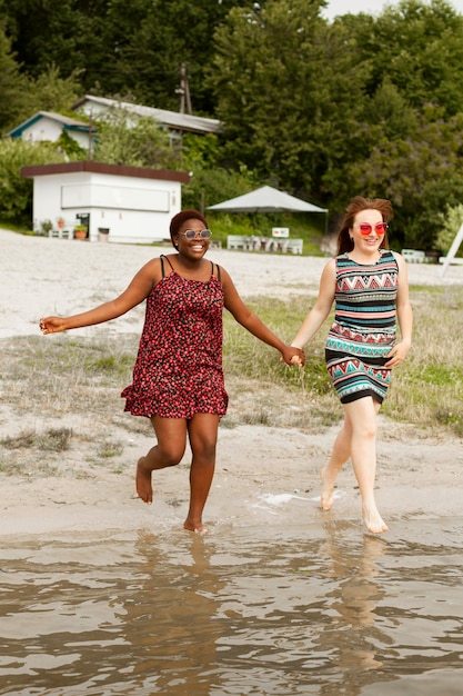 Women at the beach holding hands and running in the water