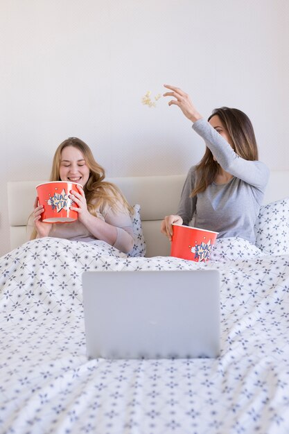 Женщины в постели бросают попкорн