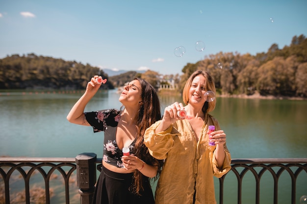 Женщины дуют пузыри возле реки