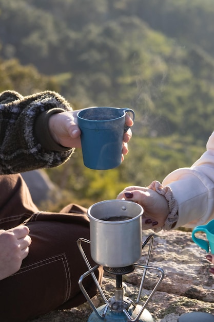 Free photo women boiling tea on portable camp stove outdoors