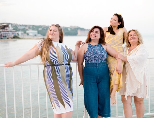 Women in casual clothes leaning on a fence