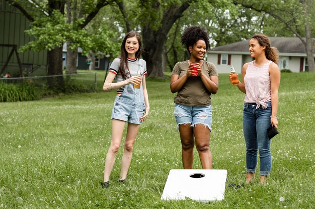Women chatting during a cornhole game in the park