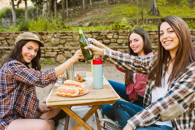 Women clinking bottles in nature