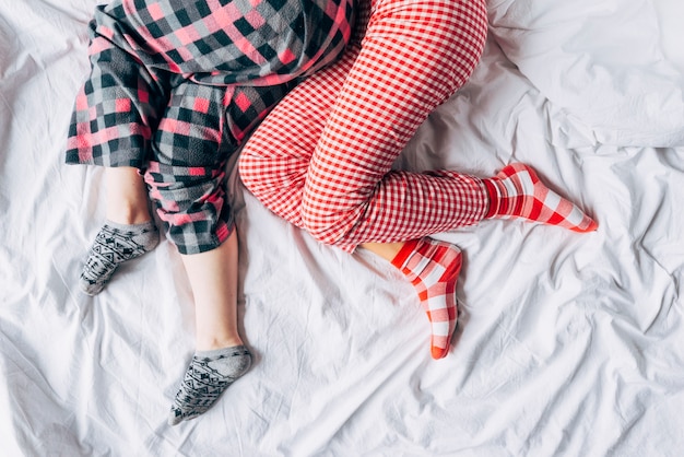 Women in colored pajamas and socks sleeping on bed