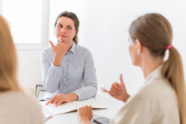 Free photo women conversing at table using sign language