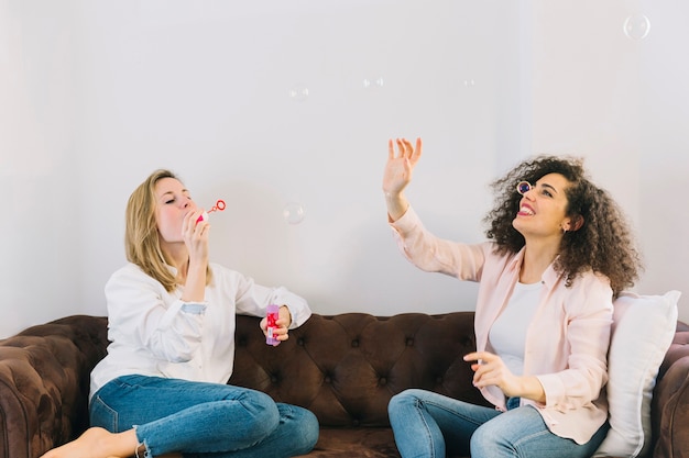 Women on couch blowing bubbles