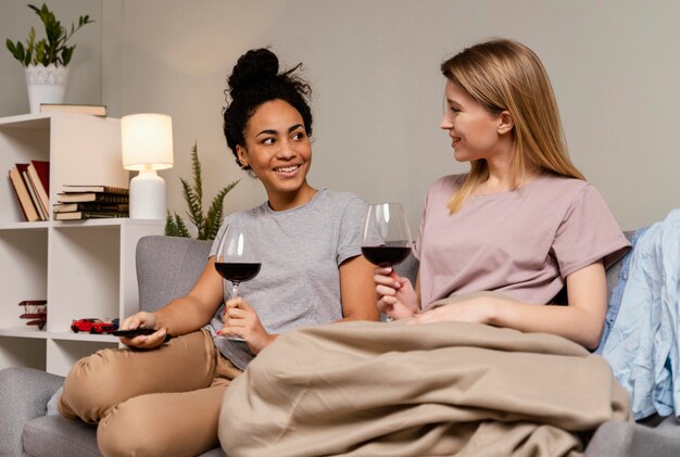 Women on couch watching tv and drinking wine