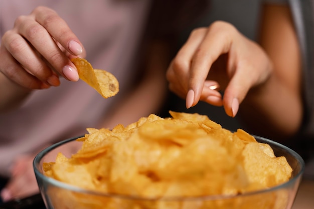 Women on couch watching tv and eating chips close up