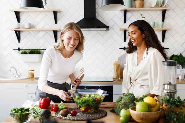 women of different nationalities are happy and cooking a salad in the kitchen