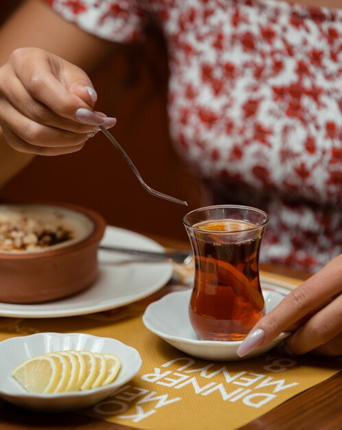 レモンと伝統的なアゼルバイジャングラスで紅茶を飲む女性