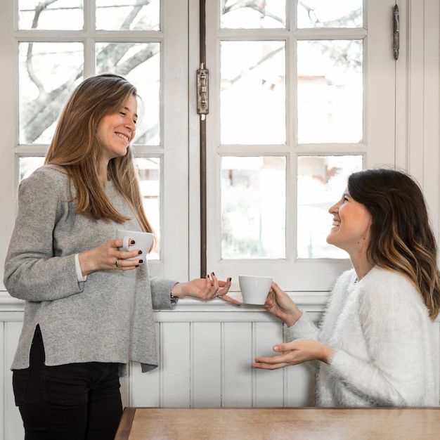 ウィンドウの近くのコーヒーを飲む女性