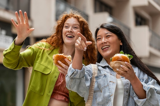 Женщины едят вкусные гамбургеры на улице