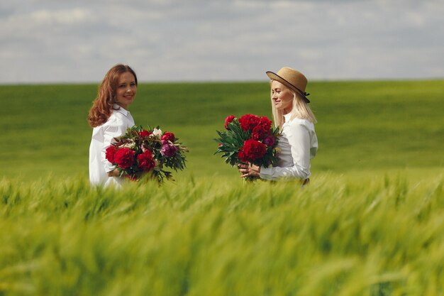 Women in elegant clothes standing in a summer field