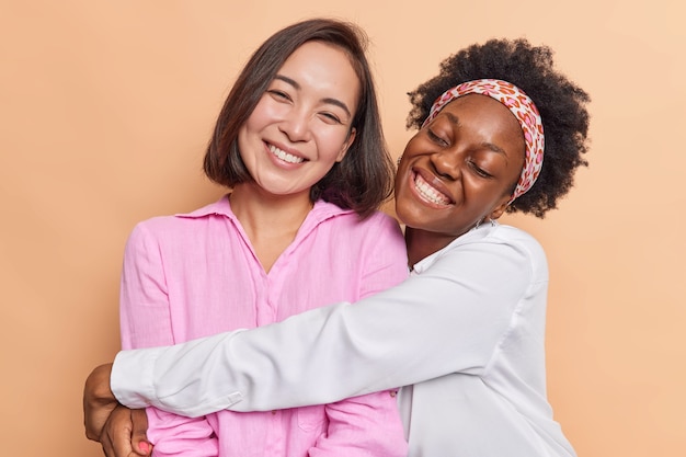 Free photo women embrace and have friendly relationship love each other dressed casually enjoy spending time together isolated on beige