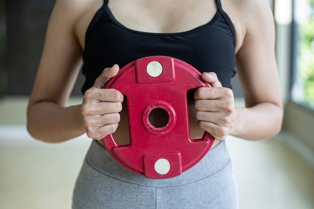 Женщины упражняются с гантелями весовой пластин в груди.