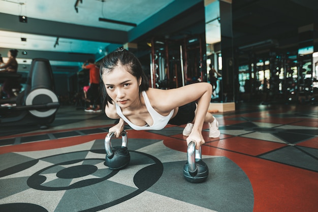 Women exercising by pushing the floor with the Kettlebell in the gym.