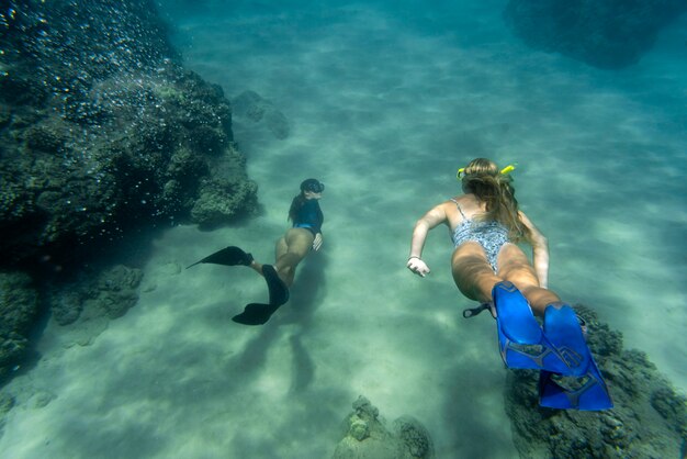 Women freediving with flippers underwater