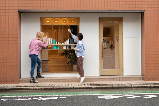 Women getting the display window of a japanese hairdressers ready