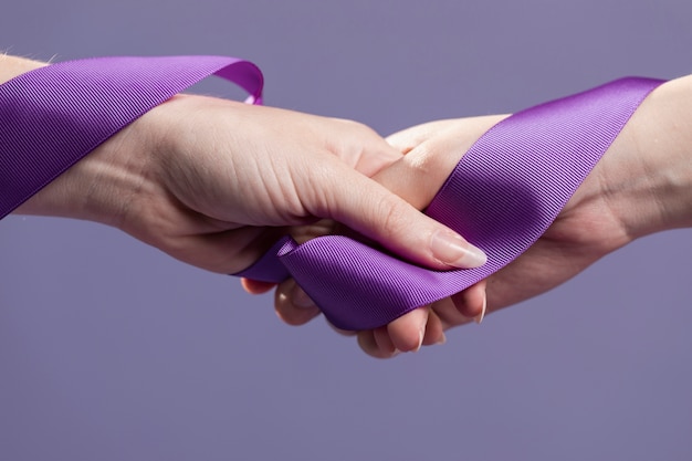 Women hands holding purple satin ribbon