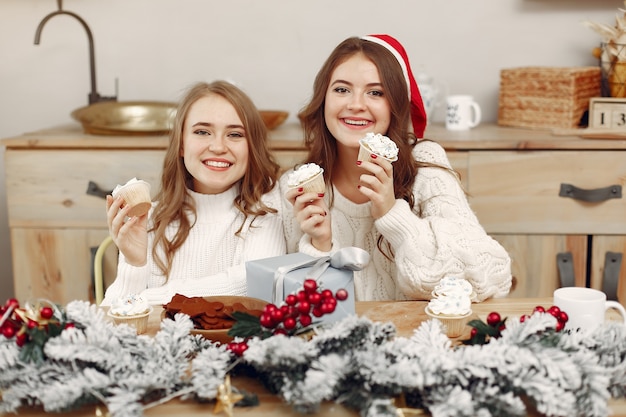 Free photo women have a cupcakes. friends in a christmass decorations. girl in a santa's hat.